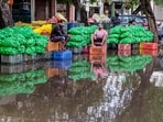 Vendors sit outside shops on a waterlogged road following rainfall, in Gurugram, Haryana, on Wednesday. (PTI)