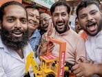 BJP supporters show a bulldozer model as they celebrate the party’s West Bengal win, in Lucknow on Monday. (PTI PHOTO)