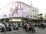 TOPSHOT - Iranians drive past a huge billboard carrying the image of the late Iranian supreme leader Ayatollah Ali Khamenei, killed in February 2026 in a military attack by the US and Israel on Iran.
