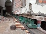 The building has been lifted using a network of jacks. Green hydraulic jacks hold the structure from below, while grey jacks —fitted with rollers — are used to move it forward. (HT Photo)