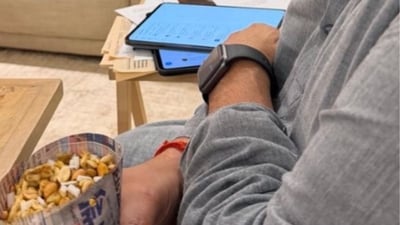 In the image, Goenka appears seated indoors, looking at a tablet while snacking on jhalmuri. (X@hvgoenka) In the image, Goenka appears seated indoors, looking at a tablet while snacking on jhalmuri. (X@hvgoenka)