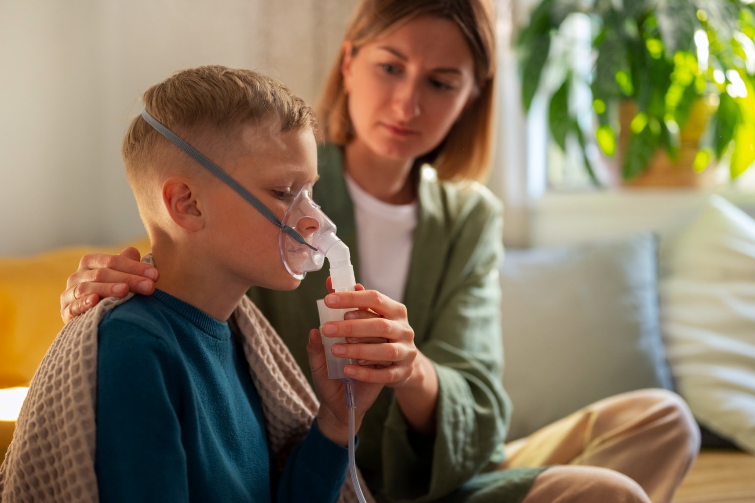 The parent helps the child to use a nebuliser. (Picture credit: Freepik)