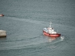 Crew members wearing hazmat suites leave the port on an ambulance boat towards the cruise ship MV Hondius.