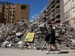 People walk at the site of an earlier Israeli strike on the southern suburbs of Beirut, Lebanon.