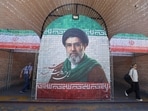 Iranian commuters walks past a large tiled image of Iran's current leader Ayatollah Mojtaba Khamenei, at the entrance to the metro in Tehran.