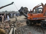 A crane removes a burned armored vehicle from a damaged police checkpost site following a car bombing attack by militants in the Fateh Khel area of Pakistan's Bannu.