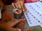 A polling officer puts indelible ink on the index finger of a woman voter. A polling officer puts indelible ink on the index finger of a woman voter.