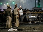 Police personnel stand beside charred vehicles at the blast site after an explosion near the Red Fort in the old quarters of Delhi.