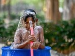 Children bathing in water drums in Noida Sector 94 to find relief from the scorching heat.
