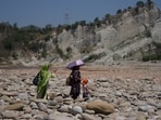 A woman carries an umbrella to protect herself from the heat on a hot summer day on the outskirts of Jammu on Sunday. (AP Photo)