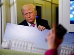 A member of the media raises her hand to ask a question as US President Donald Trump speaks while holding up renderings of the planned White House ballroom, aboard Air Force One en route to Joint Base Andrews, Maryland, US, March 29, 2026. 