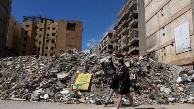 People walk at the site of an earlier Israeli strike on the southern suburbs of Beirut, Lebanon. (REUTERS)