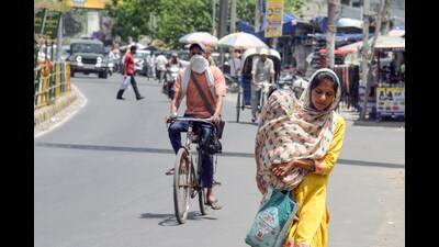 A woman covering herself and a child in her arms with a stole, walks on a road amid the scorching sun and heatwaves, in Jalandhar on Wednesday. (ANI) A woman covering herself and a child in her arms with a stole, walks on a road amid the scorching sun and heatwaves, in Jalandhar on Wednesday. (ANI)