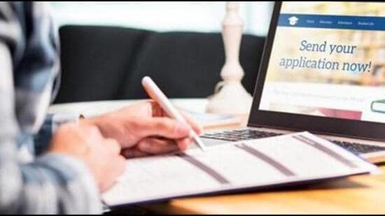 Young man writing college or university application form with pen and paper. Student applying or filling document. Scholarship, grant or admission. School website in laptop. (Getty Images/iStockphoto)