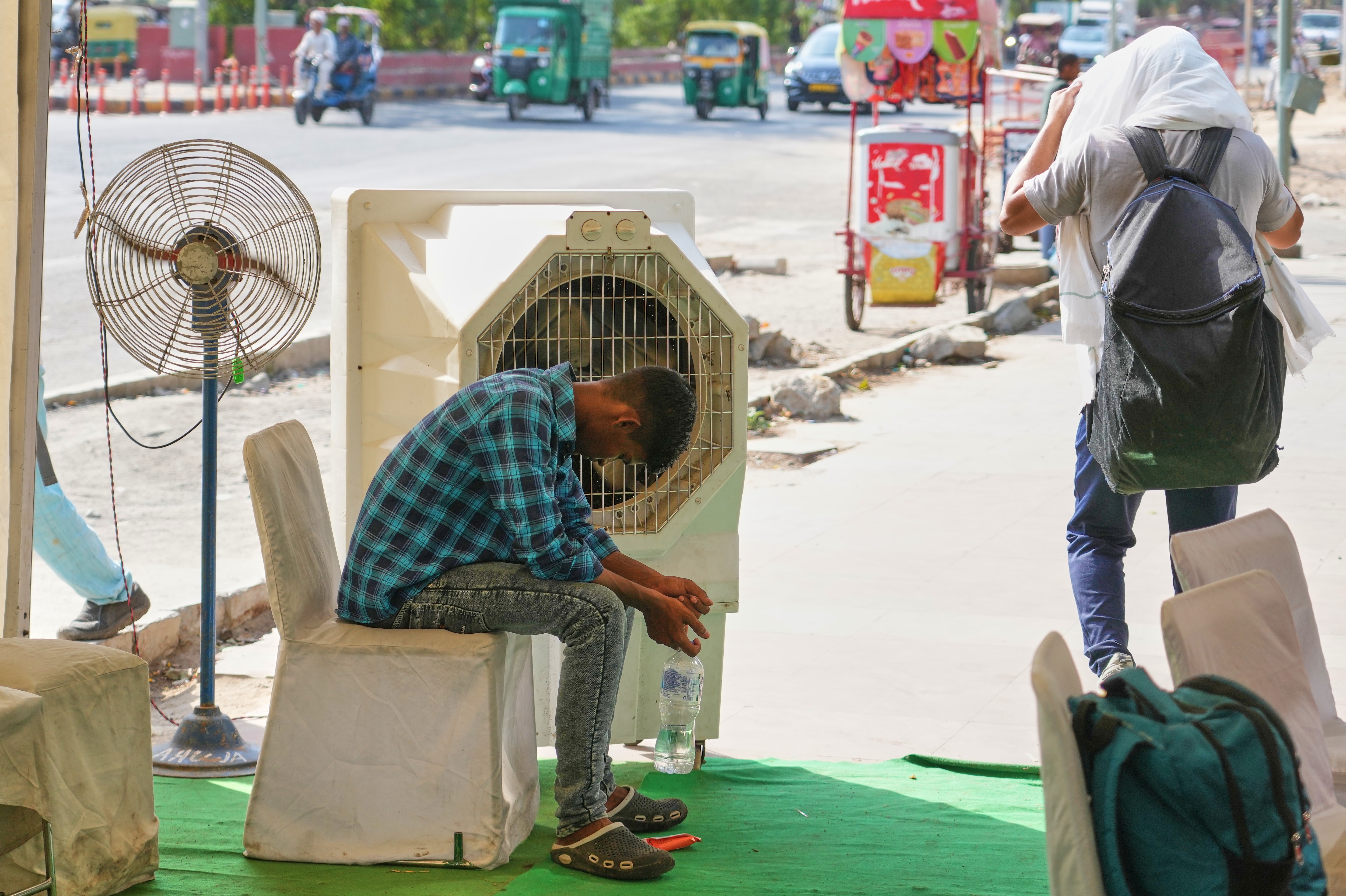 A man sits in front of a water cooler at a roadside cooling station set up by the government in New Delhi, India, Wednesday, May 20, 2026. (AP )