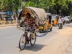 A man rides a bicycle fitted with a makeshift canopy on a hot summer day in Hyderabad, Telangana.