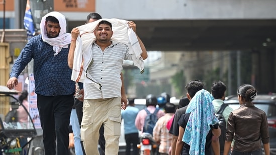 Noida, India-May 23, 2026:To protect themselves from the scorching heat, commuters cover themselves with clothing and use umbrellas.. The India Meteorological Department has issued an orange alert across the National Capital Region warning of severe heatwave conditions.The maximum daytime temperature ranged between 44 degree celsius and 45 degree celsius, in Noida, India, on Saturday, May 23, 2026. (Photo by Sunil Ghosh / Hindustan Times)