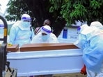 Congolese medical workers wearing personal protective equipment (PPE) load a coffin of a patient that died of Ebola on a mobile trailer at the Rwampara General Hospital.