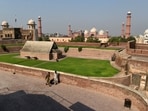 People walk on the premises of Lahore Fort with the historic Badshahi Mosque in the background, in Lahore. 