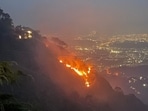 The forest fire on the slopes of the Kasauli hills on Tuesday night. The Chandigarh tricity lights are visible in the backdrop. (HT Photo)