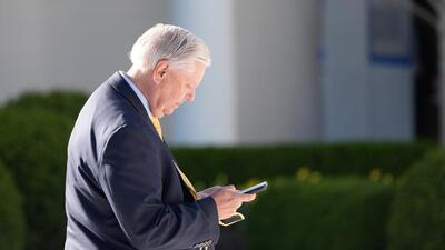 Sen. Lindsey Graham looks at his phone in the Rose Garden before President Donald Trump arrives on Marine One on the South Lawn of the White House. (AP FILE PHOTO) Sen. Lindsey Graham looks at his phone in the Rose Garden before President Donald Trump arrives on Marine One on the South Lawn of the White House. (AP FILE PHOTO)