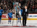 Retired Colorado Avalanche player Claude Lemieux waves to fans as he is honored 