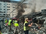 Rescuers work at the site of an Israeli airstrike that hit a building and damaged a hospital, seen in the background, in the southern port city of Tyre, Lebanon