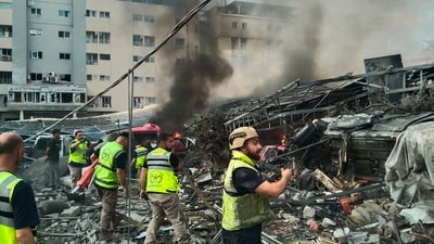 Rescuers work at the site of an Israeli airstrike that hit a building and damaged a hospital, seen in the background, in the southern port city of Tyre, Lebanon (AP Photo/undefined) Rescuers work at the site of an Israeli airstrike that hit a building and damaged a hospital, seen in the background, in the southern port city of Tyre, Lebanon (AP Photo/undefined)