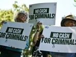 Demonstrators hold signs protesting US President Donald Trump's IRS settlement in Washington