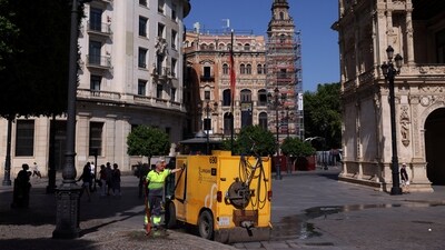 A worker holds a water flexible tube next to a small Lipasam truck during a heatwave, in Seville, Spain on July 3, 2025. (REUTERS)