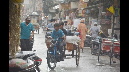 Commuters caught in the rain in Amritsar on Thursday. (Sameer Sehgal/HT)