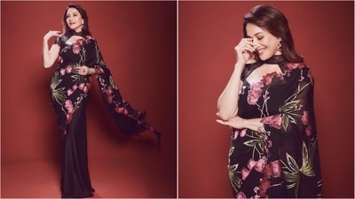 Madhuri looked stunning in a black saree adorned with vibrant red and green floral prints, elevating the look with chic cut-out halter-neck blouse. (Instagram/@madhuridixitnene) Madhuri looked stunning in a black saree adorned with vibrant red and green floral prints, elevating the look with chic cut-out halter-neck blouse. (Instagram/@madhuridixitnene)