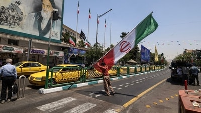 A worker raises the Iranian flag in central Tehran. A worker raises the Iranian flag in central Tehran.