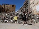 People walk at the site of an earlier Israeli strike on the southern suburbs of Beirut, Lebanon.