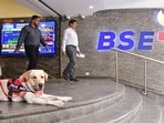 A security personnel with a sniffer dog keeps vigil as people walk out of the Bombay Stock Exchange building in Mumbai.