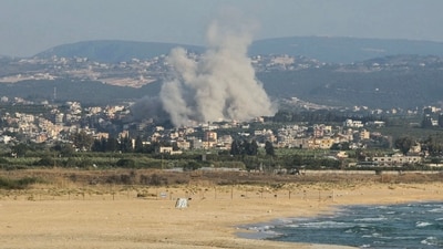 FILE: A photograph taken from the southern city of Tyre shows people sunbathing on the beach as smoke rises from the site of an Israeli airstrike in the village of Deir Qanoun Ras al-Ain on June 8, 2026. (AFP) FILE: A photograph taken from the southern city of Tyre shows people sunbathing on the beach as smoke rises from the site of an Israeli airstrike in the village of Deir Qanoun Ras al-Ain on June 8, 2026. (AFP)