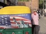 An auto-rickshaw is parked on a Delhi roadside bearing a “Happy Birthday America!” placard announcing the forthcoming 250th anniversary of American independence. (HT Photo)