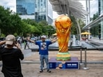 A man poses for a picture next to a replica of the World Cup trophy in downtown Houston, Texas, on June 10, 2026, ahead of the 2026 FIFA World Cup