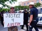 An Austin Metcalf supporter holds a sign as law enfrocement officilals walk past in front of the Collin County courthouse during the Karmelo Anthony trial.