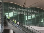 People stand on an escalator as they enter Noida International Airport (NIA), in Noida.