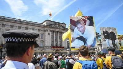 A protestor holds a photo of Britain's former Prince Andrew, outside Buckingham Palace after the King's Birthday Parade "Trooping the Colour" in London on June 13, 2026. (Photo by JUSTIN TALLIS / AFP) (AFP)
