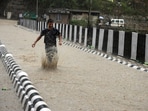 A child playing in water logged Suketi khad bridge after heavy rain in Mandi on Tuesday. (Birbal Sharma/HT)