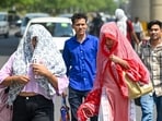 Despite relatively moderate temperatures, the sun remained intense, prompting commuters to cover their heads with cloth and use umbrellas to shield themselves from the harsh sunlight, in Noida, India, on Friday, June 19, 2026.
