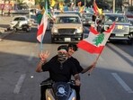 Youths ride scooters and vehicles while waving flags of Iraq, Iran, Lebanon and Hezbollah in Baghdad on June 15, 2026, during celebrations following the announcement of a deal to end the war between Iran and the US.