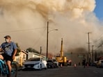 A person rides a bicycle as a massive warehouse fire at a cold storage facility continues to burn and spread smoke around the city on June 20, 2026 in Los Angeles, California. (Photo by MARIO TAMA / GETTY IMAGES NORTH AMERICA / Getty Images via AFP)