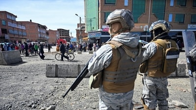People walk near military personnel standing on guard as they are deployed, after Bolivian President Rodrigo Paz declared a nationwide state of emergency following weeks of violence and blockades, in El Alto, Bolivia (REUTERS)