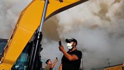 Onlookers use their phones to document the massive warehouse fire at a cold storage facility continues to burn and spread smoke around the city on June 20, 2026 in Los Angeles, California. (Photo by MARIO TAMA / GETTY IMAGES NORTH AMERICA / Getty Images via AFP) (Getty Images via AFP) Onlookers use their phones to document the massive warehouse fire at a cold storage facility continues to burn and spread smoke around the city on June 20, 2026 in Los Angeles, California. (Photo by MARIO TAMA / GETTY IMAGES NORTH AMERICA / Getty Images via AFP) (Getty Images via AFP)