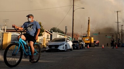 A person rides a bicycle as a massive warehouse fire at a cold storage facility continues to burn and spread smoke around the city on June 20, 2026 in Los Angeles, California. (Photo by MARIO TAMA / GETTY IMAGES NORTH AMERICA / Getty Images via AFP) (Getty Images via AFP) A person rides a bicycle as a massive warehouse fire at a cold storage facility continues to burn and spread smoke around the city on June 20, 2026 in Los Angeles, California. (Photo by MARIO TAMA / GETTY IMAGES NORTH AMERICA / Getty Images via AFP) (Getty Images via AFP)