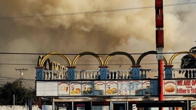 A person sits at a bus stop as a massive warehouse fire at a cold storage facility continues to burn and spread smoke around the city on June 20, 2026 in Los Angeles, California. (Photo by MARIO TAMA / GETTY IMAGES NORTH AMERICA / Getty Images via AFP) (Getty Images via AFP) A person sits at a bus stop as a massive warehouse fire at a cold storage facility continues to burn and spread smoke around the city on June 20, 2026 in Los Angeles, California. (Photo by MARIO TAMA / GETTY IMAGES NORTH AMERICA / Getty Images via AFP) (Getty Images via AFP)