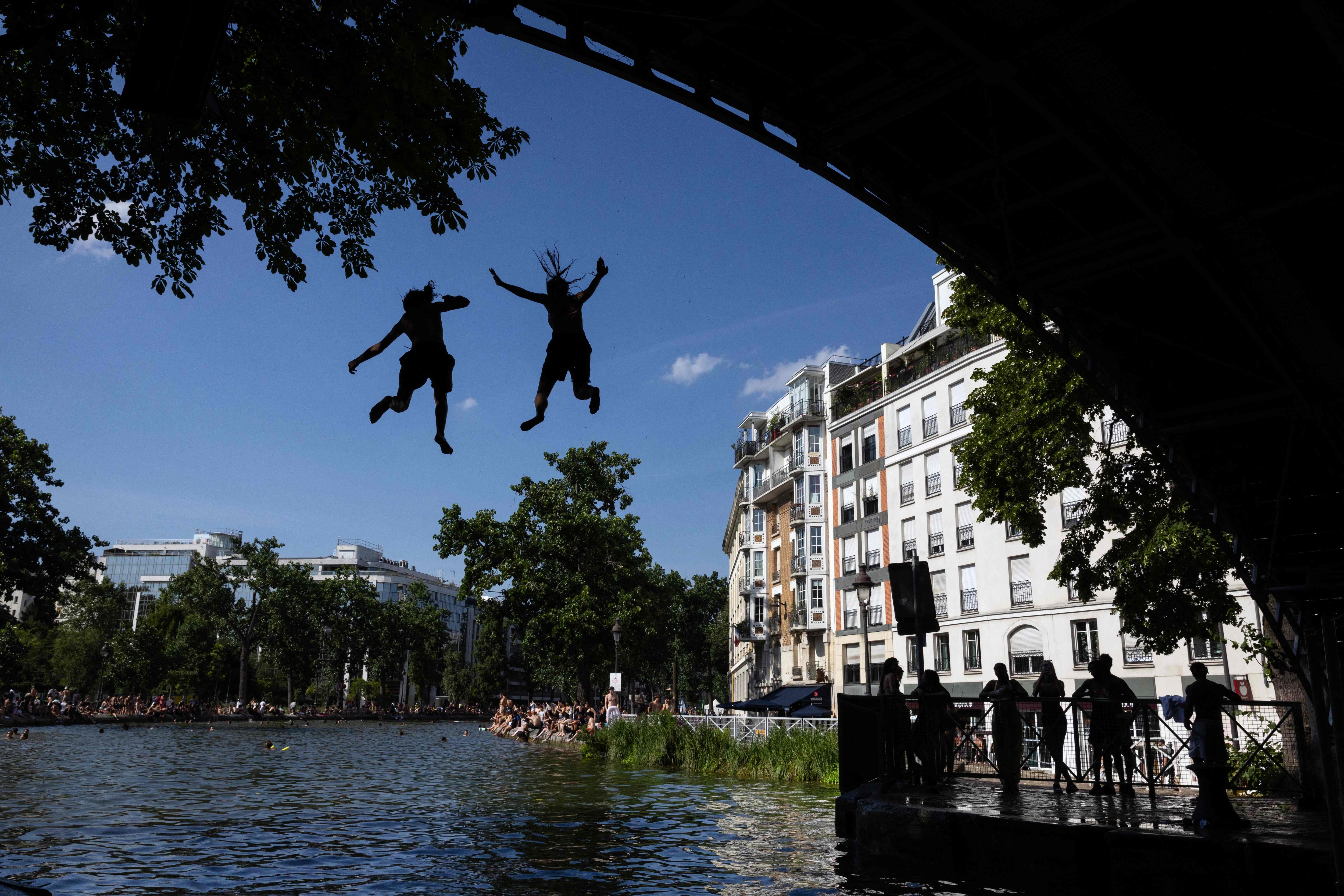 Young people jump from a bridge into the Canal Saint-Martin during a heatwave in Paris. (Photo by JOEL SAGET / AFP) (AFP) Young people jump from a bridge into the Canal Saint-Martin during a heatwave in Paris. (Photo by JOEL SAGET / AFP) (AFP)